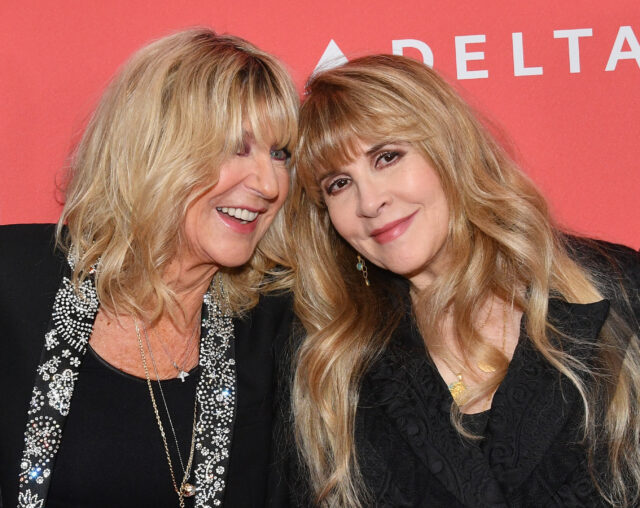 Christine McVie and Stevie Nicks standing together on a red carpet