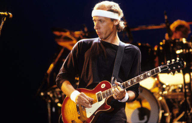 Mark Knopfler playing the electric guitar on stage