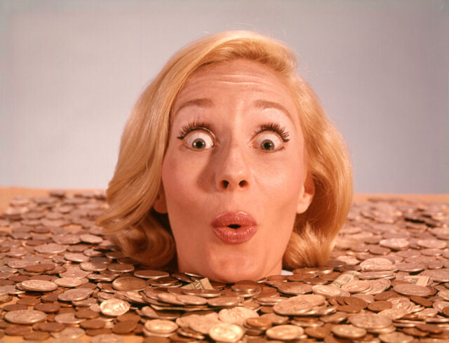 Woman sticking her head out of a pile of coins