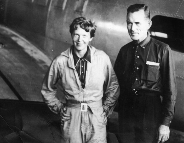 Amelia Earhart and Fred Noonan standing with their aircraft