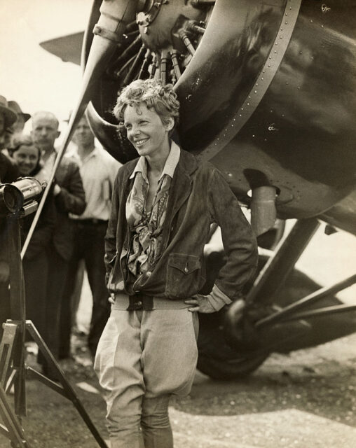 Amelia Earhart standing in front of her aircraft