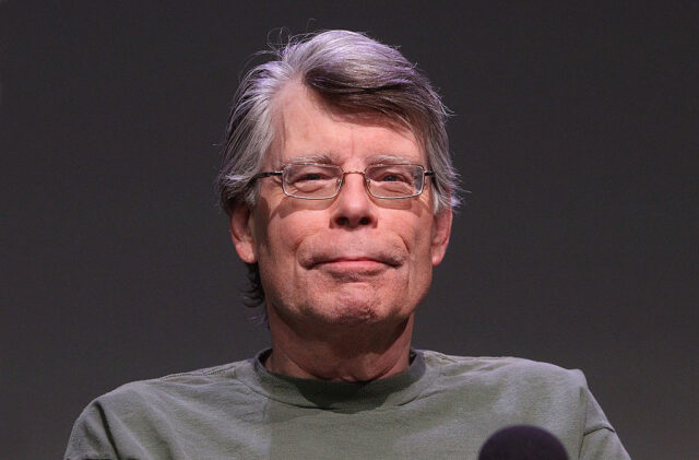 Stephen King sitting in front of a microphone