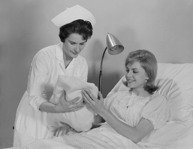 Nurse handing a new mom her baby