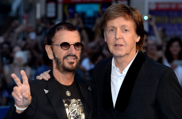Paul McCartney and Ringo Starr. Starr holds up a peace sing with his fingers.
