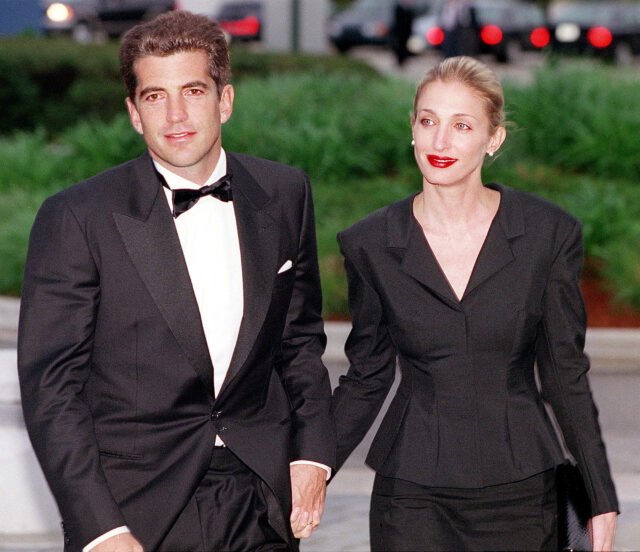 JFK Jr. and Carolyn Bessette Kennedy holding hands in fancy clothes.