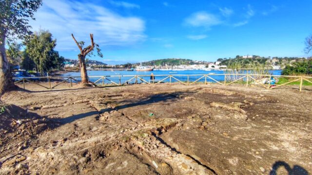 An excavation site with a body of water in the background.