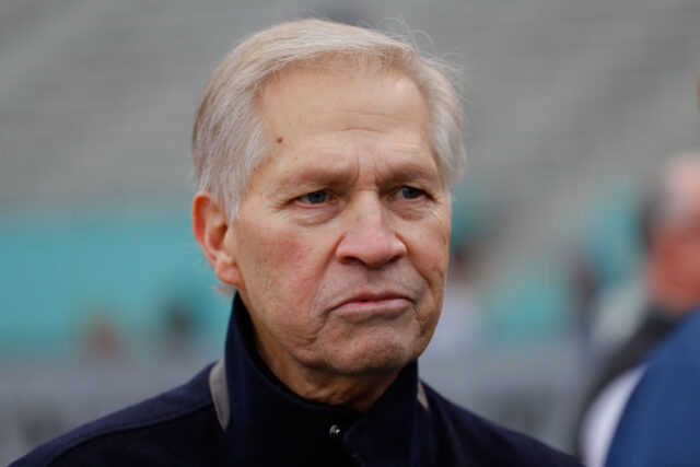 Chris Mortensen standing on a football field with other men