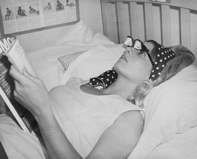 A woman laying reading with horizontal glasses.
