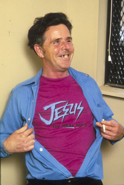 Henry Lee Lucas wearing a pink Jesus t-shirt under a blue shirt.