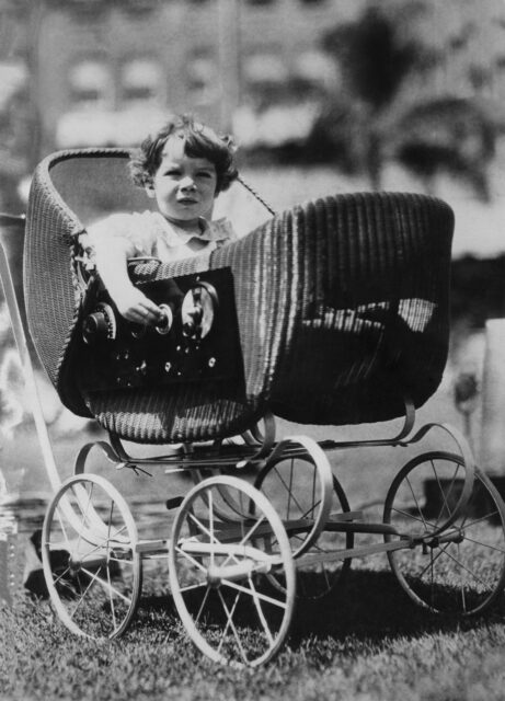 A child in a pram with a radio on the side.