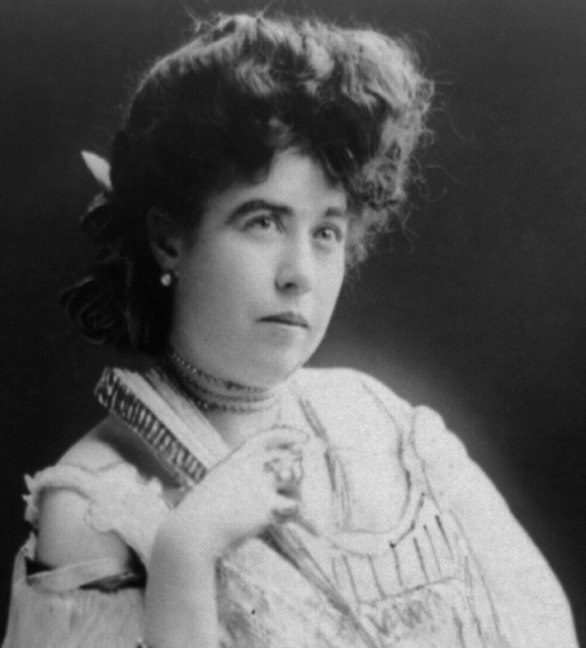 Mrs. James J. "Molly" Brown, survivor of the Titanic, three-quarter length portrait, standing, facing right, right arm on back of chair.