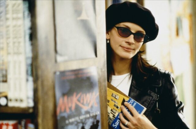Julia Roberts peering out from a corner, wearing sunglasses and a beret.