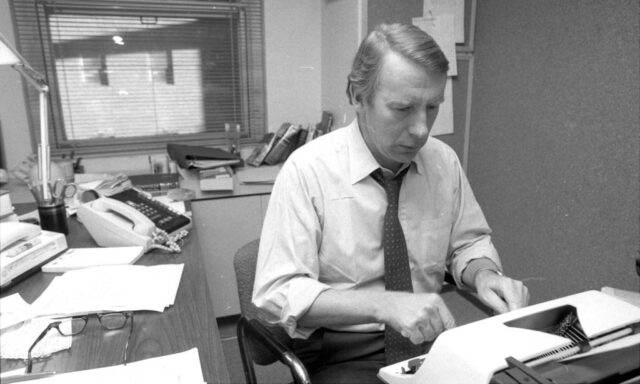Robert MacNeil typing on a typewriter at a desk