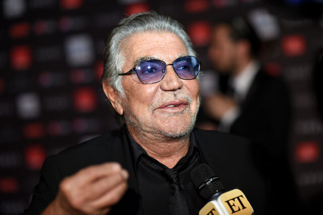 Roberto Cavalli speaking into a microphone while standing on a red carpet