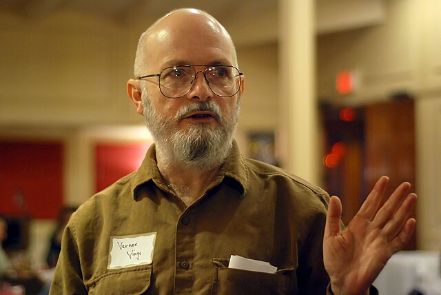 Vernor Vinge standing with his hand out in front of him