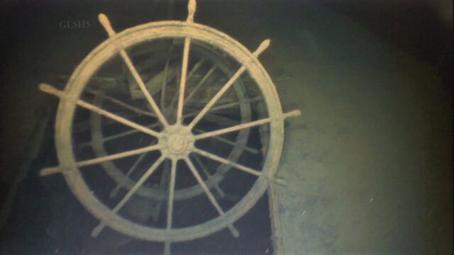 A photo of a ship's steering wheel underwater.