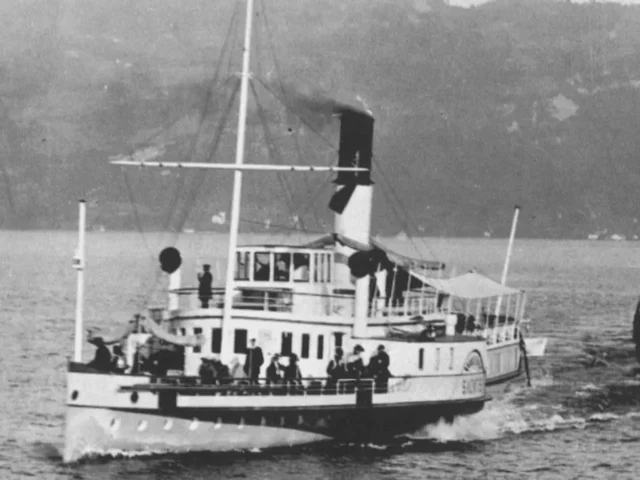 The front of a steamboat with people on it.