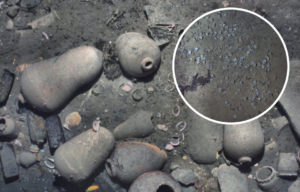 Debris scattered across the ocean floor + Broken tea cups half-buried in the sand on the ocean floor
