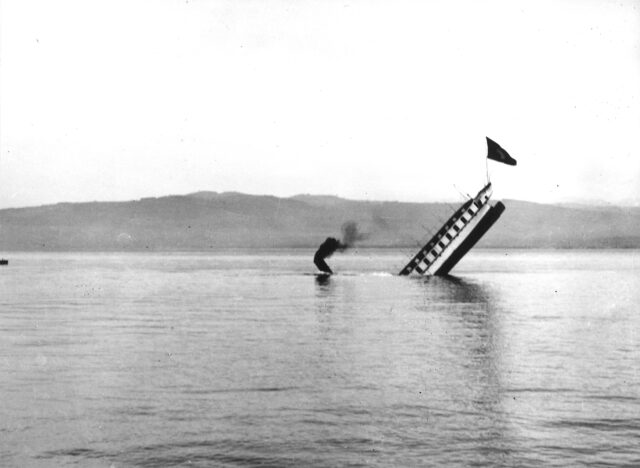 The stern of a ship sticking out of water as it sinks.
