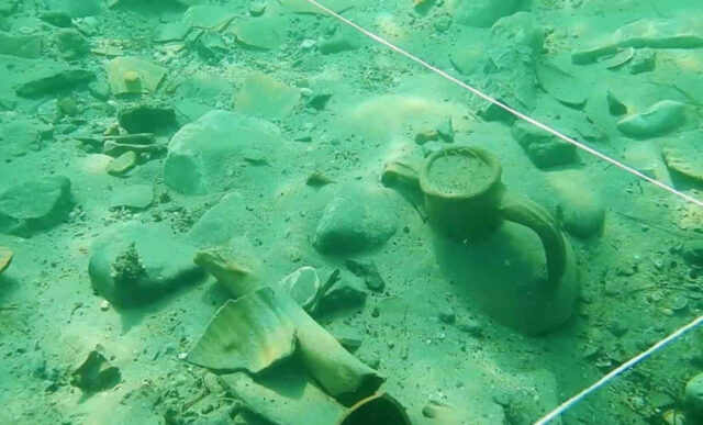 Amphorae pieces buried in the sand underwater.