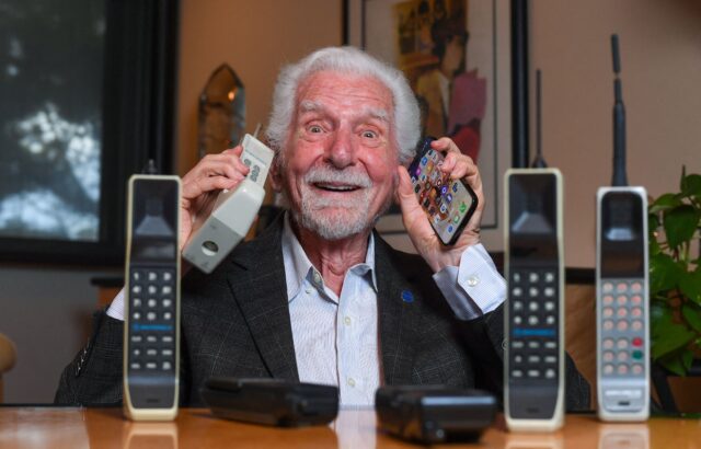 Martin Cooper holds an old and new cellphone to his ears.