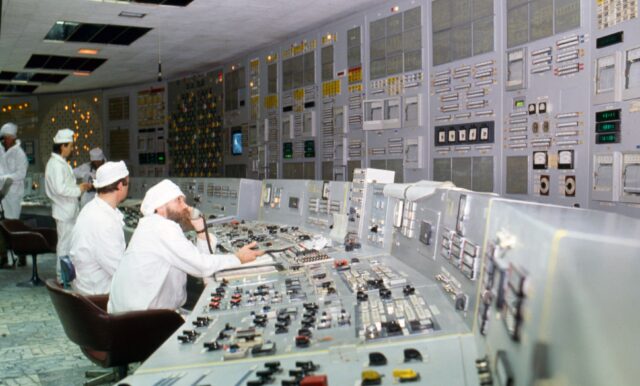 Multiple workers sitting inside a control room.