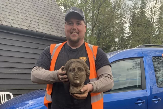 A construction worker holding a Roman bust.