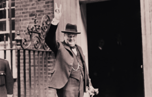 Prime Minister Winston Churchill smiling outside 10 Downing Street, holding hands in a "v" for victory