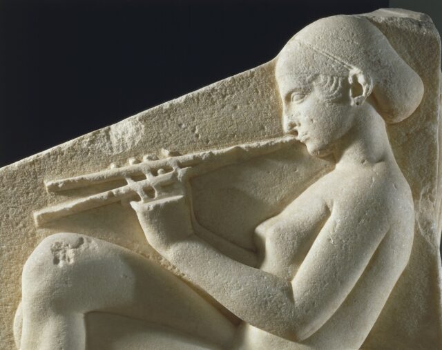 A stone sculpture of a woman playing a flute.