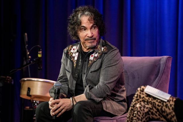 John Oates sitting with his hands clasped.
