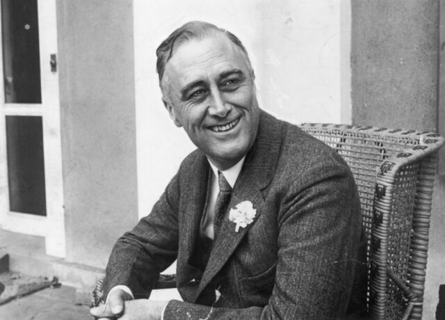 President Franklin D Roosevelt smiling while seated in wicker chair 