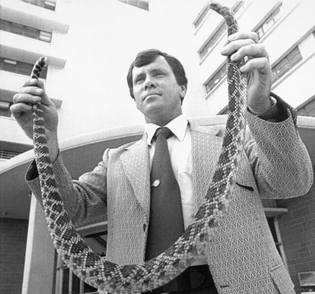 A man holds a snake.