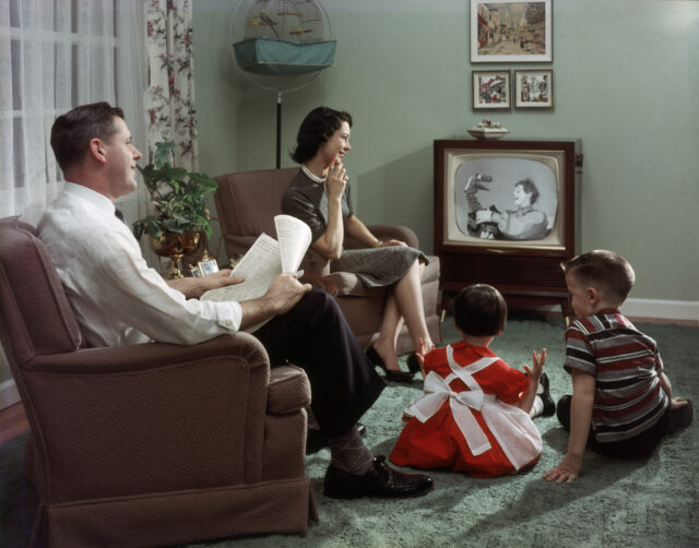A family sits around their television.