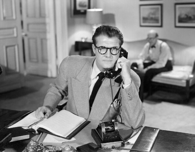 George Reeves wearing glasses and talking on the phone.