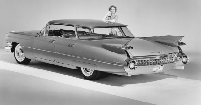 A woman models a 1950s car.
