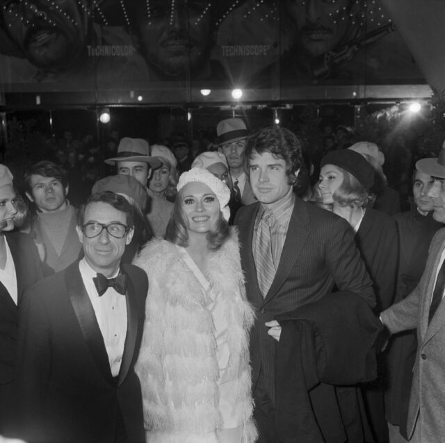 Warren Beatty and Faye Dunaway surrounded by people.