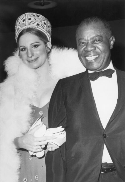 Barbra Streisand and Louis Armstrong smiling together.
