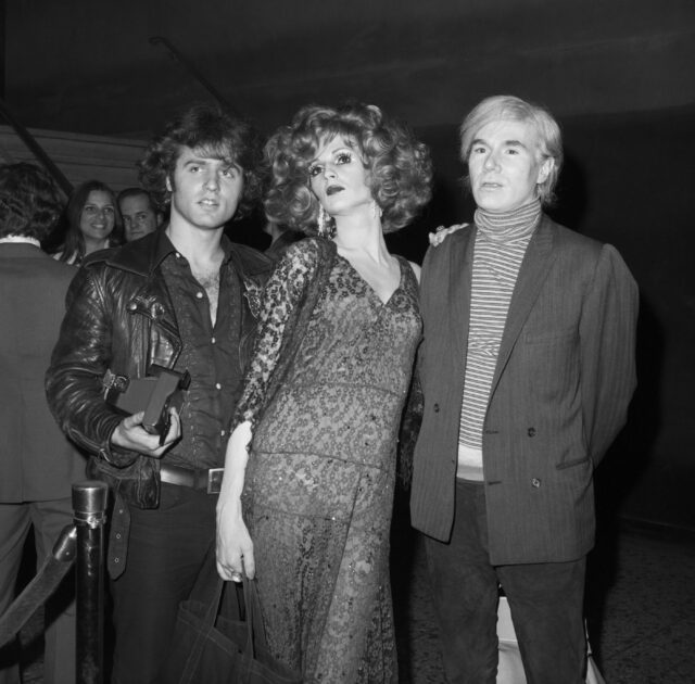 Gerard Malanga, Candy Darling, and Andy Warhol standing together for a photo.