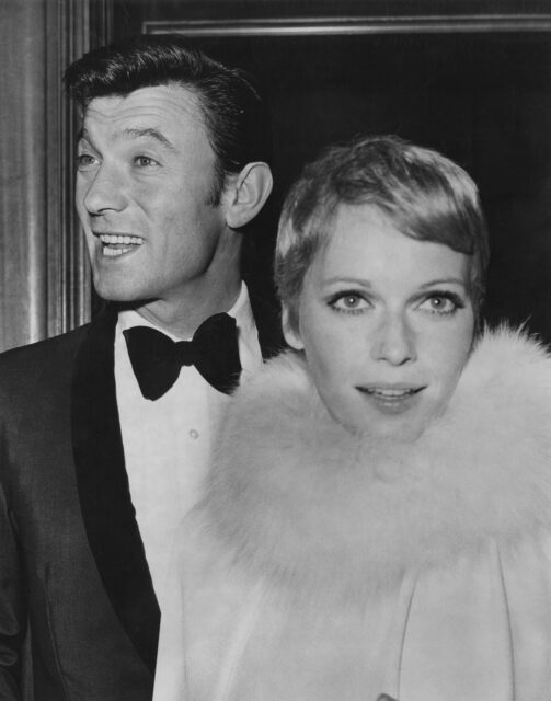 Laurence Harvey stands behind Mia Farrow.
