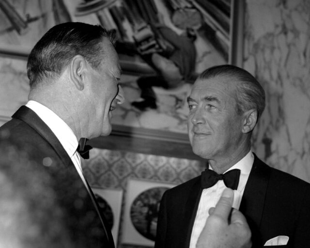 John Wayne and James Stewart talking to one another.