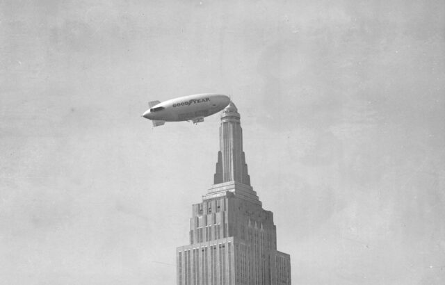 goodyear blimp flying past top of empire state buliding circa 1931